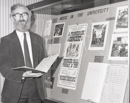 Dr Cedric Thorpe Davie stands in front of a display of text and images titled Music in the University